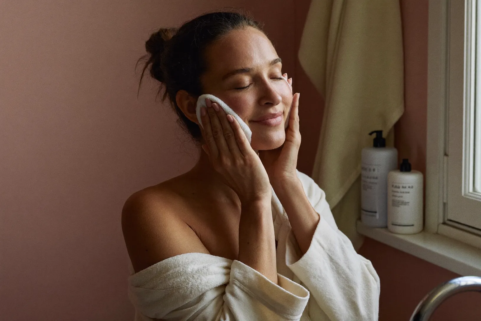 A woman gently pressing a soft towel to her freshly cleansed face